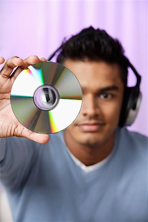 dj - young man with headphones on, holding compact disc in front of him Fotografie stock - Premium Royalty-Free, Codice: 655-02702994