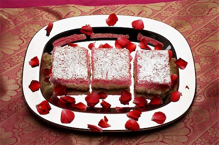 Indian pink sweets on silver tray with rose petals. Fotografie stock - Premium Royalty-Free, Codice: 655-03082830