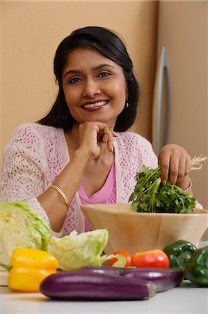 Indian woman smiling while preparing food Stock Photo - Premium Royalty-Free, Code: 655-03241676