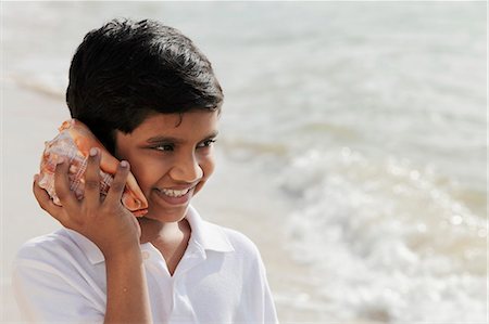 Young boy listening to sea shell Stock Photo - Premium Royalty-Free, Code: 655-03457891