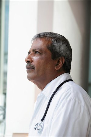 portrait of man side view - Head shot of Indian doctor looking up and thinking Stock Photo - Premium Royalty-Free, Code: 655-03457939