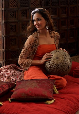 simsearch:614-08119697,k - Young woman sitting on pillows holding Indian antiques Fotografie stock - Premium Royalty-Free, Codice: 655-03457968