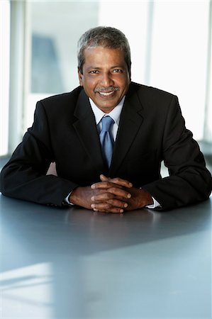 simsearch:655-03457957,k - Mature Indian business man sitting at table smiling Stock Photo - Premium Royalty-Free, Code: 655-03457961