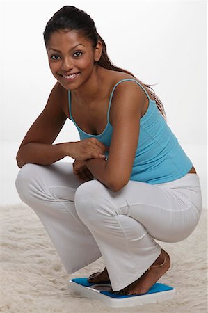 woman squatting on scale and smiling Stock Photo - Premium Royalty-Free, Code: 655-03458077