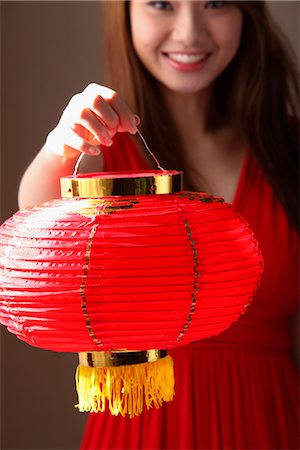 Young woman holding red lantern and smiling Stock Photo - Premium Royalty-Free, Code: 656-04926485