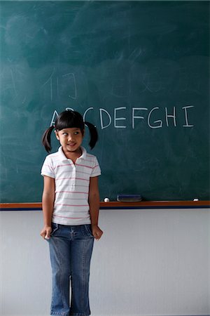 playing alphabets pictures - young girl standing in front of the chalkboard smiling Stock Photo - Premium Royalty-Free, Code: 656-04926490