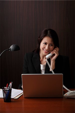 simsearch:656-04926491,k - Woman sitting at her desk talking on phone Stock Photo - Premium Royalty-Free, Code: 656-04926503