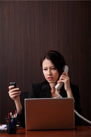 singapore business - Woman sitting at her desk multi-tasking Stock Photo - Premium Royalty-Free, Code: 656-04926523