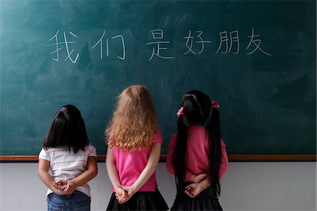 three young girls looking at Chinese characters "We are all friends" Foto de stock - Sin royalties Premium, Código: 656-04926551