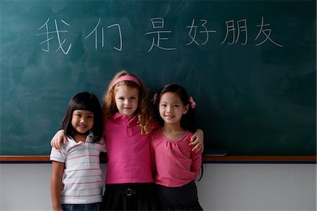 school friends standing - three young girls in front of chalk boards with Chinese writing "we are all friends." Stock Photo - Premium Royalty-Free, Code: 656-04926572