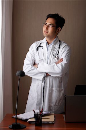 simsearch:614-03080072,k - male doctor standing at his desk looking out window Foto de stock - Sin royalties Premium, Código: 656-04926586