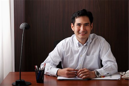 eurasian - man sitting at desk and smiling Stock Photo - Premium Royalty-Free, Code: 656-04926603