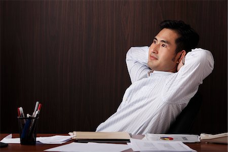 singapore business men - man relaxing at work with hands behind his head Stock Photo - Premium Royalty-Free, Code: 656-04926636