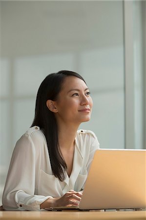 simsearch:6108-05867231,k - Singapore, Mid adult woman sitting at desk with laptop Photographie de stock - Premium Libres de Droits, Code: 656-08349927