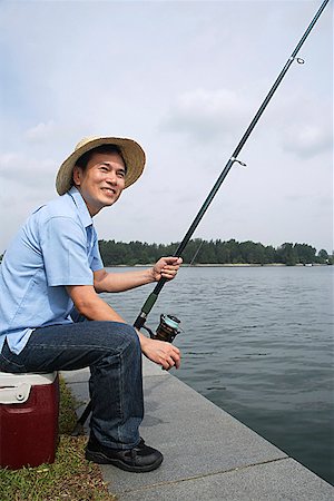 simsearch:622-02913456,k - Man sitting on cooler, fishing with fishing pole Fotografie stock - Premium Royalty-Free, Codice: 656-01765189
