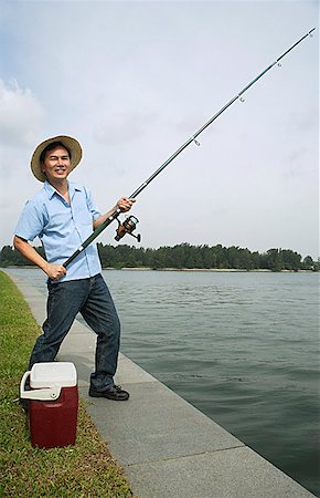 simsearch:622-02913456,k - Man fishing with fishing pole, looking at camera, smiling Fotografie stock - Premium Royalty-Free, Codice: 656-01765243