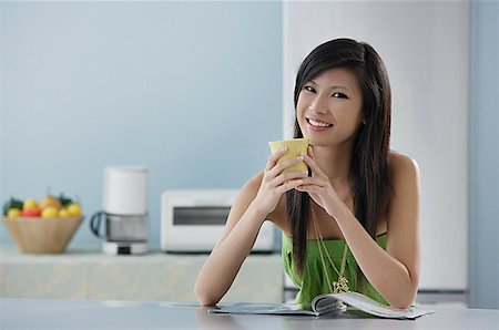 simsearch:656-01765881,k - woman sitting in kitchen with magazine and mug, smiling at camera Foto de stock - Royalty Free Premium, Número: 656-01765279