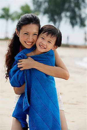 Mother hugging son on beach, son wrapped in blue towel Stock Photo - Premium Royalty-Free, Code: 656-01765316