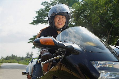 Mature woman riding motorcycle and wearing helmet Stock Photo - Premium Royalty-Free, Code: 656-01765330