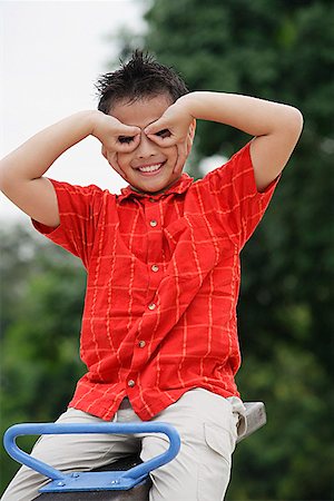 photography foolish - Boy sitting on See-Saw, making a mask with his fingers Stock Photo - Premium Royalty-Free, Code: 656-01765345