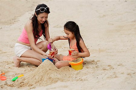 friends and buckets - Mother and daughter building sand castle on beach Stock Photo - Premium Royalty-Free, Code: 656-01765359