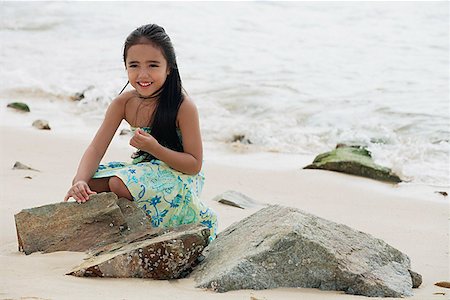 Young girl sitting on beach by rocks Stock Photo - Premium Royalty-Free, Code: 656-01765376
