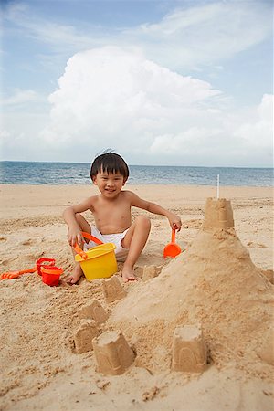 simsearch:841-03507749,k - Young boy on beach building sand castle, smiling Stock Photo - Premium Royalty-Free, Code: 656-01765419
