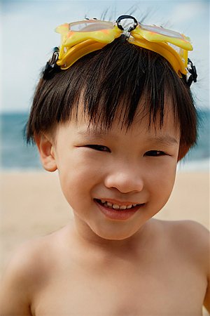 simsearch:841-03507749,k - Young boy on beach with yellow swimming goggles on head, smiling portrait Stock Photo - Premium Royalty-Free, Code: 656-01765446