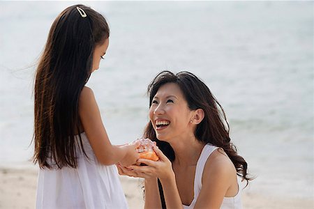 simsearch:656-01765470,k - Mother and daughter on beach, daughter handing conk shell to mother, smiling Foto de stock - Sin royalties Premium, Código: 656-01765460