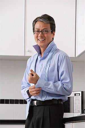 rich asian home - Man in kitchen, buttoning his shirt and tie loose around neck. smiling at camera.  Getting ready for work. Stock Photo - Premium Royalty-Free, Code: 656-01765506