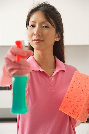 Woman cleaning with cleaning spray and sponge, spraying at camera Stock Photo - Premium Royalty-Free, Code: 656-01765508