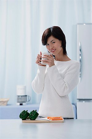 simsearch:656-01765227,k - Woman in kitchen, holding a mug, looking at camera Fotografie stock - Premium Royalty-Free, Codice: 656-01765524