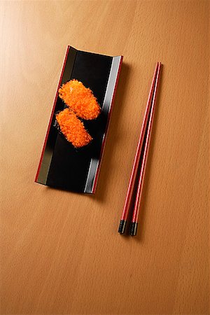 platter overhead view - two pieces of sushi, chopsticks, tobiko gunkan, fish roe Stock Photo - Premium Royalty-Free, Code: 656-01765530