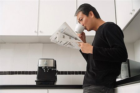 Man in kitchen, drinking coffee and reading paper Stock Photo - Premium Royalty-Free, Code: 656-01765541