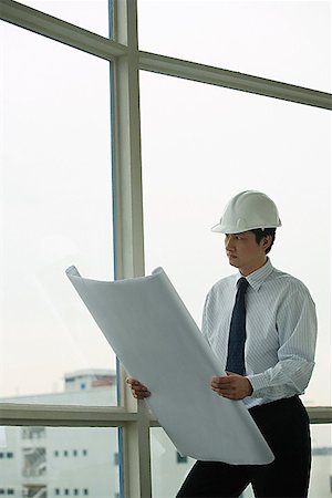 scheme - man wearing hard hat, holding blue prints, looking out window Stock Photo - Premium Royalty-Free, Code: 656-01765603