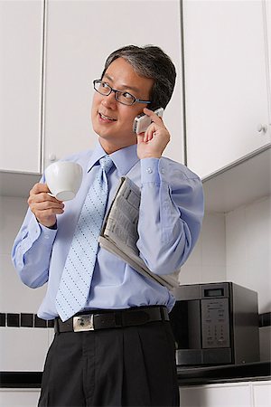 simsearch:656-03519571,k - Business Man in kitchen, talking on phone, holding coffee cup and newspaper, multi tasking. Foto de stock - Sin royalties Premium, Código: 656-01765669