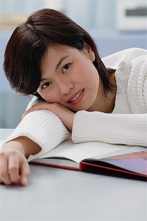 simsearch:656-01765227,k - Woman leaning on book, smiling at camera Fotografie stock - Premium Royalty-Free, Codice: 656-01765727