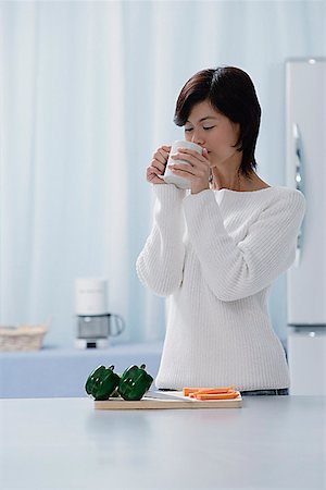 simsearch:656-01765227,k - Woman in kitchen, drinking from a cup Fotografie stock - Premium Royalty-Free, Codice: 656-01765748