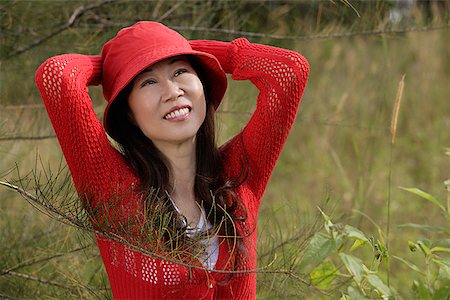 Woman wearing red hat outdoors in nature, smiling Stock Photo - Premium Royalty-Free, Code: 656-01765818