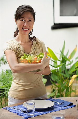 simsearch:656-01765227,k - Woman standing at outdoor table, holding bowl of salad Fotografie stock - Premium Royalty-Free, Codice: 656-01765827