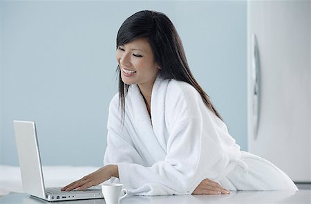 simsearch:656-01765881,k - woman wearing bathrobe in kitchen looking at computer, laptop, smiling Foto de stock - Royalty Free Premium, Número: 656-01765864