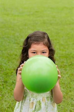 Fille debout sur l'herbe, tenant le ballon vert sur son visage Photographie de stock - Premium Libres de Droits, Code: 656-01765873