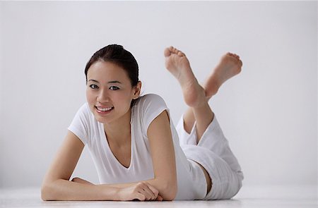 simsearch:656-01765715,k - Woman lying on stomach on floor, looking at camera, smiling Stock Photo - Premium Royalty-Free, Code: 656-01765916