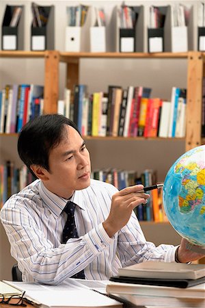 A man working with a globe on the desk Stock Photo - Premium Royalty-Free, Code: 656-01766010