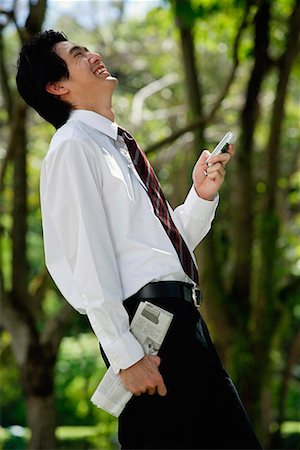 simsearch:656-01766118,k - A man laughs as he checks his cellphone in the park Foto de stock - Royalty Free Premium, Número: 656-01766100