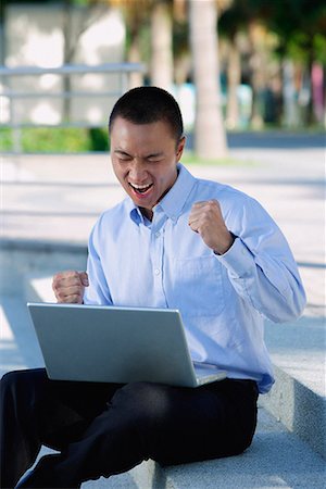 simsearch:656-01766255,k - A man is excited as he uses his laptop outdoors Stock Photo - Premium Royalty-Free, Code: 656-01766141