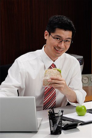 simsearch:656-01766255,k - A man eats lunch at his desk Stock Photo - Premium Royalty-Free, Code: 656-01766235