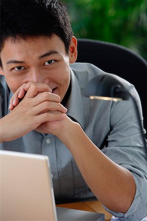 simsearch:656-01766255,k - A man smiles at the camera as he sits at his desk Stock Photo - Premium Royalty-Free, Code: 656-01766259