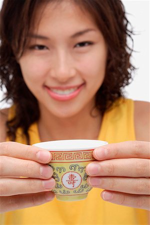 A woman looks at the camera as she holds out a cup of tea Stock Photo - Premium Royalty-Free, Code: 656-01766283