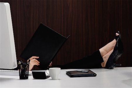 executive mentor - A woman puts her feet up on her desk as she reads from a folder Stock Photo - Premium Royalty-Free, Code: 656-01766382